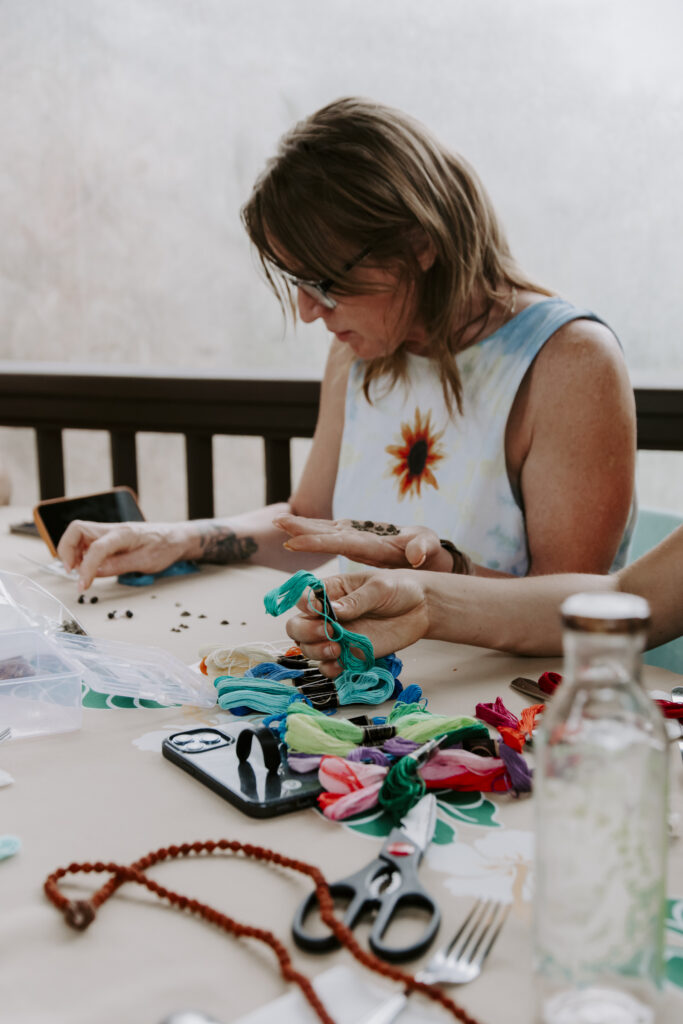 A woman creating a mala bead necklace while during training for becoming a certified yoga instructor