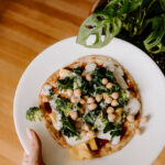 Holding a white plate with a mini veggie pizza