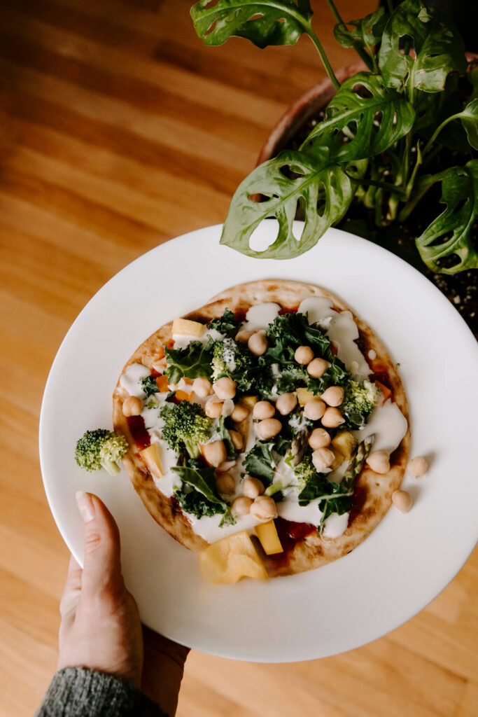 Holding a white plate with a mini veggie pizza